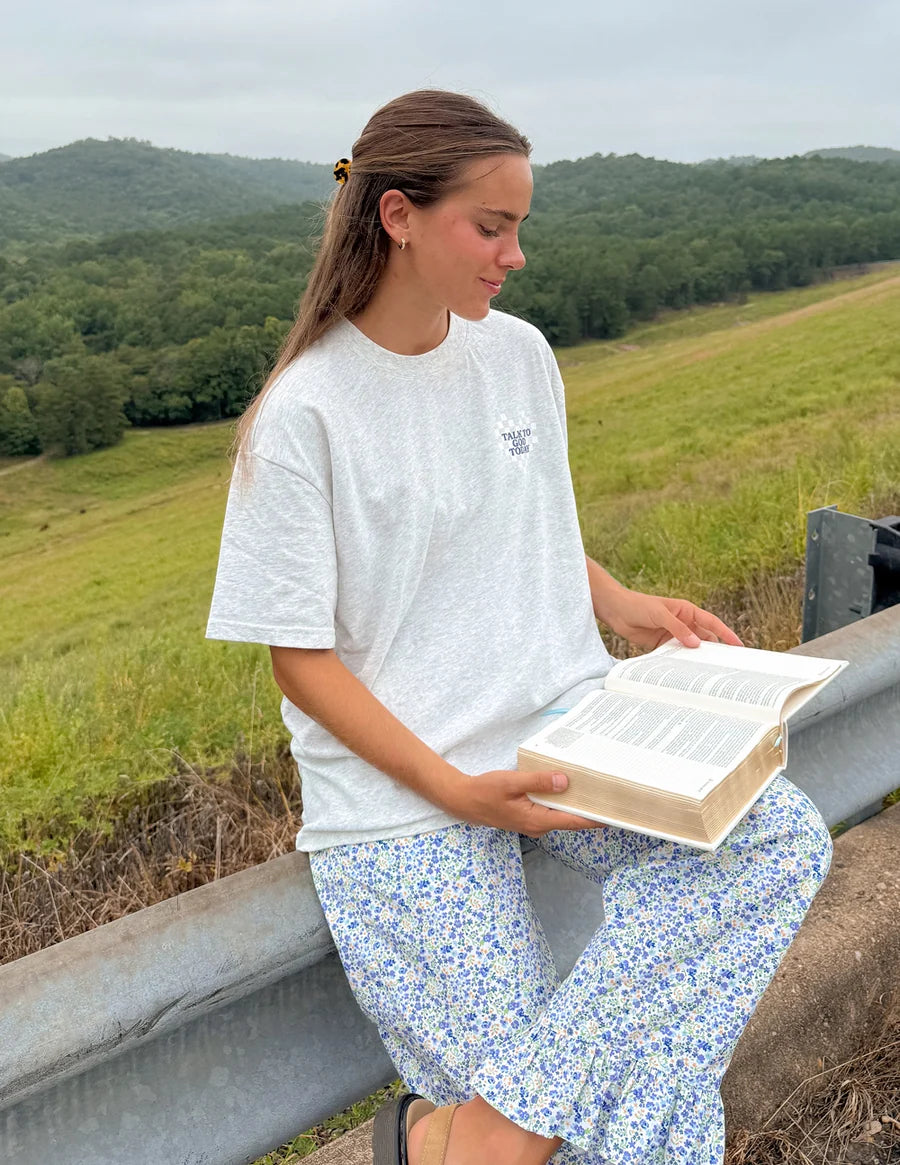 Woman reading a bible outdoors in a scenic landscape in a have you talked to God today t shirt